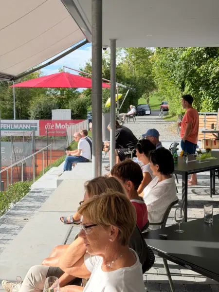 Zuschauerinnen und Zuschauer auf der Terrasse des Clubhauses